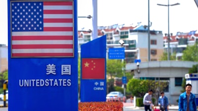 People walk by a display boards featuring the U.S. and Chinese flags.