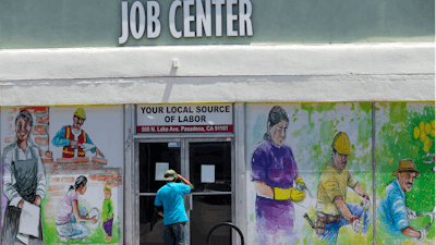 In this May 7, 2020 file photo, a person looks inside the closed doors of the Pasadena Community Job Center in Pasadena, CA during the coronavirus outbreak.