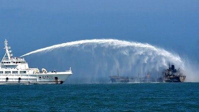 A rescue vessel tries to put out fire emerging from an oil tanker.