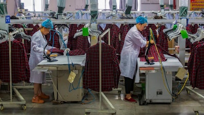 Workers iron shirts in an apparel factory.