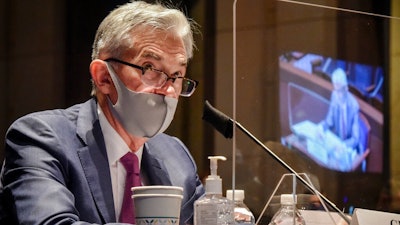 In this June 30, 2020, file photo Federal Reserve Board Chairman Jerome Powell, reflected in the sneeze guard set up between himself and members of the House Committee on Financial Services, speaks during a hearing on oversight of the Treasury Department and Federal Reserve pandemic response on Capitol Hill in Washington. With the economy still in the pandemic’s grip, the Federal Reserve is facing a decision on whether to stretch an emergency lending program in a way that could bring more risk for the government and taxpayers. Lawmakers are pressing the central bank to deliver more aid to struggling small and mid-sized businesses.