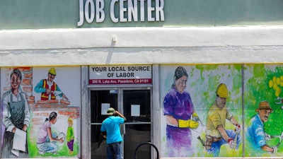 In this May 7, 2020, file photo, a person looks inside the closed doors of the Pasadena Community Job Center in Pasadena, Calif., during the coronavirus outbreak. President Donald Trump’s plan to offer a stripped-down boost in unemployment benefits to millions of Americans amid the coronavirus outbreak has thus far found little traction among the states, which would be required to pick up a quarter of the cost to deliver the maximum benefit.