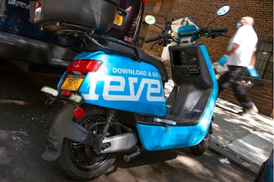 A man passes a parked Revel scooter on New York's Upper West Side, Tuesday, July 28, 2020. The moped sharing startup Revel suspended its New York City service Tuesday, July 28, 2020 after its second customer death in 10 days. The company's blue scooters, which require no training to rent, had been seen as an alternative to taxis and subways during the coronavirus pandemic.
