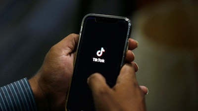 In this July 21, 2020 file photo, a man opens social media app 'TikTok' on his cell phone, in Islamabad, Pakistan. Walmart said Thursday, Aug. 27, that it's interested in teaming up with Microsoft to buy the U.S. business of TikTok, the popular Chinese video app.