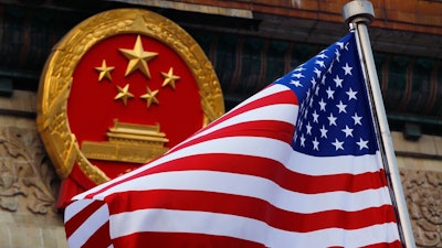 In this Nov. 9, 2017, file photo, an American flag is flown next to the Chinese national emblem during a welcome ceremony for visiting U.S. President Donald Trump outside the Great Hall of the People in Beijing. U.S. and Chinese trade envoys discussed strengthening coordination of their government’s economic policies during a phone meeting, the Ministry of Commerce announced.