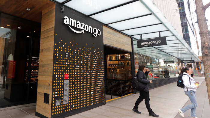 In this March 4, 2020 file photo, people walk out of an Amazon Go store, in Seattle. Amazon is rolling out a new device for contactless transactions that will scan an individual’s palm. The Amazon One, which will initially launch in two Amazon Go stores in Seattle, is being viewed as a way for people to use their palm to make everyday activities like paying at a store easier.