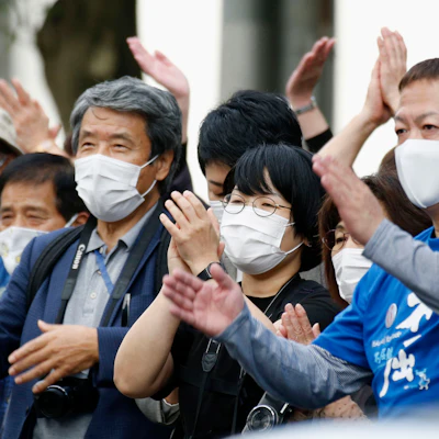 People celebrate in front of the Sendai High Court, Sendai, Japan, Sept. 30, 2020.