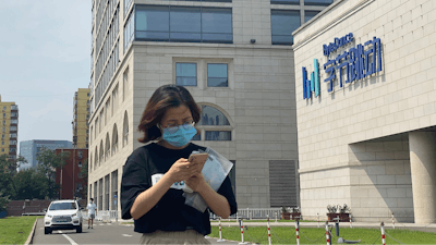 A woman uses her phone as she passes by the ByteDance headquarters in Beijing, China.
