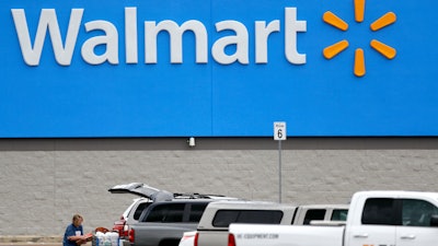 A woman pulls groceries from a cart to her vehicle outside of a Walmart store.
