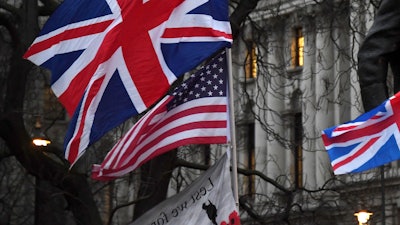 In this file photo dated Friday, Jan. 31, 2020, Brexit supporters hold British and US flags during a rally in London.