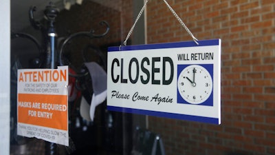 A closed sign hangs in the window of a barber shop.
