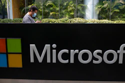 A man wearing a mask looks at this phone outside the Microsoft office in Beijing, China.