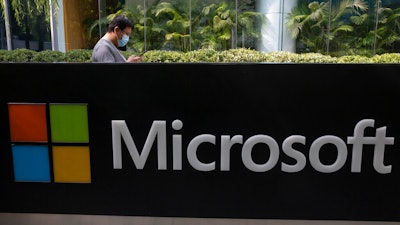 A man wearing a mask looks at this phone outside the Microsoft office in Beijing, China.