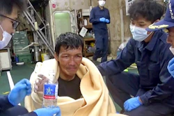In this image made from video released by the 10th Regional Japan Coast Guard Headquarters, a rescued crew member of a Panamanian cargo ship takes a bottle of water as he speaks to Japanese Coast Guard members off the Amami Oshima, Japan Wednesday, Sept. 2, 2020. Japanese rescuers have safely plucked the crew member from the sea while searching for the cargo ship carrying more than 40 crew and thousands of cows went missing after sending a distress call off the southern Japanese island.