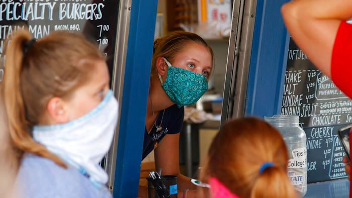 A staffer wears a mask while taking orders at a small restaurant in Grand Lake, Colo.