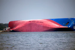 A Moran tugboat nears the stern of the capsizing vessel Golden Ray.