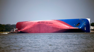 A Moran tugboat nears the stern of the capsizing vessel Golden Ray.