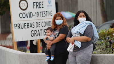 Two women and a child wait to take a coronavirus test at a mobile testing site.