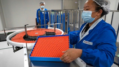A worker feeds vials for production of SARS CoV-2 Vaccine for COVID-19