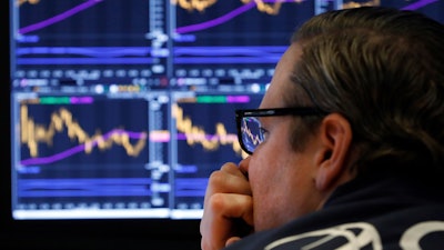 In this Jan. 28, 2020 photo, specialist Gregg Maloney watches the screens at his post on the floor of the New York Stock Exchange.