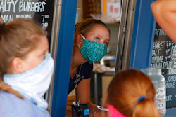 A staffer wears a mask while taking orders at a small restaurant in Grand Lake, Colo.