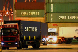 Trucks transport shipping containers at a dockyard in Qingdao in east China's Shandong province.
