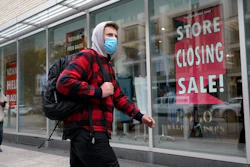 A passer-by walks past a store closing sign, right, in the window of a department store on Tuesday, Oct. 27 in Boston.