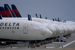 In this May 14, 2020 file photo, several dozen mothballed Delta Air Lines jets are parked on a closed runway at Kansas City International Airport in Kansas City, Mo. Delta Air Lines is the first carrier to report financial results for the third quarter, and the numbers are grim. Delta said Tuesday, Oct. 13 that it lost nearly $6.9 billion as travel remain depressed over the normally peak vacation season because of the pandemic.