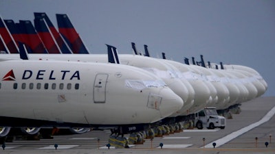 In this May 14, 2020 file photo, several dozen mothballed Delta Air Lines jets are parked on a closed runway at Kansas City International Airport in Kansas City, Mo. Delta Air Lines is the first carrier to report financial results for the third quarter, and the numbers are grim. Delta said Tuesday, Oct. 13 that it lost nearly $6.9 billion as travel remain depressed over the normally peak vacation season because of the pandemic.