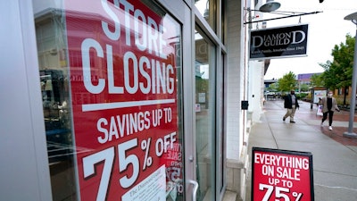 In this Wednesday, Sept. 2, 2020, file photo, passers-by walk past a business storefront with store closing and sale signs in Dedham, Mass. U.S. employers advertised for slightly fewer jobs in August while their hiring ticked up modestly. The Labor Department said Tuesday, Oct. 6, 2020, that the number of U.S. job postings on the last day of August dipped to 6.49 million, down from 6.70 million July.