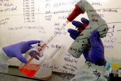 In this July 30, 2020 file photo, Kai Hu, a research associate transfers medium to cells, in the laboratory at Imperial College in London. Imperial College is working on the development of a COVID-19 vaccine. South Africa and India on Friday Oct. 2, 2020, asked the World Trade Organization to waive some provisions in the international agreements that regulate intellectual property rights, to speed up efforts to prevent, treat and contain the COVID-19 pandemic and make sure developing countries are not left behind.