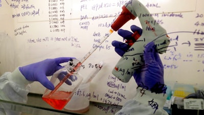 In this July 30, 2020 file photo, Kai Hu, a research associate transfers medium to cells, in the laboratory at Imperial College in London. Imperial College is working on the development of a COVID-19 vaccine. South Africa and India on Friday Oct. 2, 2020, asked the World Trade Organization to waive some provisions in the international agreements that regulate intellectual property rights, to speed up efforts to prevent, treat and contain the COVID-19 pandemic and make sure developing countries are not left behind.