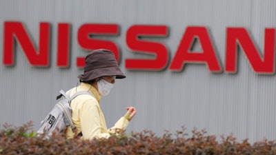 A woman walks past the corporate logo at Nissan Motor Co.'s global headquarters in Yokohama, near Tokyo, on May 21, 2020.