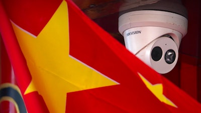 A Chinese flag hangs near a Hikvision security camera outside of a shop in Beijing on Oct. 8, 2019.