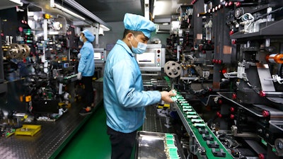 Workers place batteries on a machine at a factory manufacturing lithium batteries.