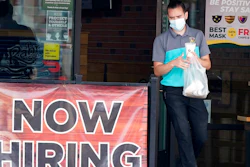 In this Sept. 2, 2020 file photo, a customer wears a face mask as they carry their order past a now hiring sign at an eatery in Richardson, Texas. The number of Americans seeking unemployment benefits fell last week to 751,000, the lowest since March, but it's still historically high and indicates the viral pandemic is still forcing many employers to cut jobs.