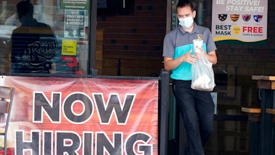 In this Sept. 2, 2020 file photo, a customer wears a face mask as they carry their order past a now hiring sign at an eatery in Richardson, Texas. The number of Americans seeking unemployment benefits fell last week to 751,000, the lowest since March, but it's still historically high and indicates the viral pandemic is still forcing many employers to cut jobs.