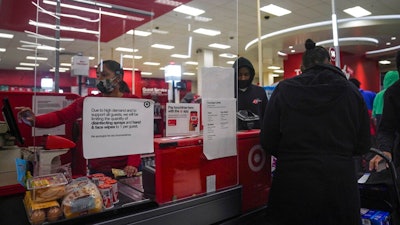 An associate, left, ring customer purchases at a Target store, Tuesday Oct. 20, 2020, in New York. The coronavirus pandemic is transforming holiday hiring this year, with companies starting hiring earlier and offering extra safety protocols. Target said it expects to hire more than 100,000 people for the holiday season.