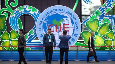 A visitor poses for photos in front of a display at the China International Import Expo in Shanghai, Nov. 5, 2020.