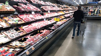 In this May 10, 2020 file photo, a shopper pushes his cart past a display of packaged meat in a grocery store in southeast Denver.