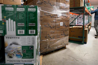 Ray Bellia stocks shelves with personal protective gloves, used by medical and law enforcement professionals, while unpacking pallets of other PPE goods in the warehouse of his Body Armor Outlet store on Dec. 9 in Salem, NH.