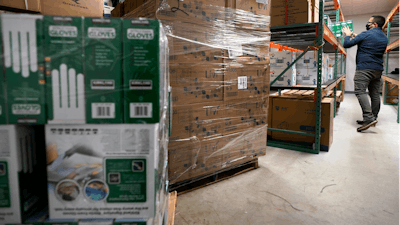 Ray Bellia stocks shelves with personal protective gloves, used by medical and law enforcement professionals, while unpacking pallets of other PPE goods in the warehouse of his Body Armor Outlet store on Dec. 9 in Salem, NH.