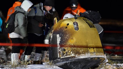 Recovery crew members check on the capsule of the Chang'e 5 probe.