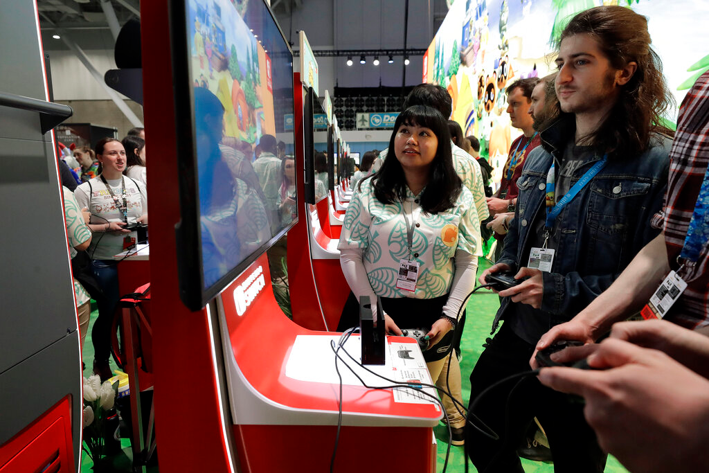 Visitors to the Pax East conference play the Nintendo Switch video game Animal Crossing, Feb. 27, 2020, in Boston.