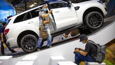 In this Sept. 26, 2020, file photo, a visitor wearing a face mask to protect against the coronavirus looks at an SUV vehicle on display at the Beijing International Automotive Exhibition, also known as Auto China, in Beijing. China’s sales of SUVs, minivans and sedans rose by double digits in November as the country recovered from the coronavirus pandemic but were below pre-virus levels for the year to date, an industry group reported Friday.