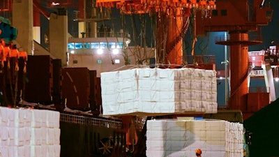 In this Sept. 25, 2020, file photo, a worker looks at goods being loaded onto a container ship at a dockyard in Qingdao in east China's Shandong province. China’s politically sensitive trade surplus with the U.S. soared to a record $75.4 billion November as exports surged 21.1% over a year earlier, propelled by strong demand from American consumers, customs data showed Monday, Dec. 7, 2020.