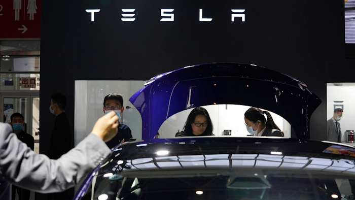 In this Sunday, Sept. 27, 2020, file photo, attendees wearing masks to protect from the coronavirus look at cars at the Tesla booth during the Auto China 2020 show in Beijing. Tesla Inc. is balking at recalling about 159,000 vehicles with potentially defective touch screens, so U.S. safety regulators are moving to force the company to take action, in news announced Wednesday, Jan. 13, 2021.