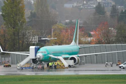 In this Nov. 18, 2020 photo, workers stand near a Boeing 737 Max airplane parked at Renton Municipal Airport next to the Boeing assembly facility in Renton, WA, where 737 Max airplanes are made.
