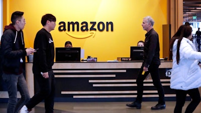 In this Nov. 13, 2018, file photo, employees walk through a lobby at Amazon's headquarters in Seattle. Amazon has announced $2 billion in loans and grants to secure affordable housing in three U.S. cities, including a Seattle suburb where the online retail giant employs at least 5,000 workers. Amazon said it would give $185.5 million to the King County Housing Authority to help buy affordable apartments in the region and keep the rents low, The Seattle Times reported Wednesday, Jan. 6, 2021.