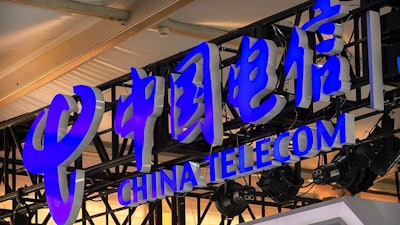 In this Sept. 5, 2020, file photo, the logo for Chinese telecommunications firm China Telecom is seen on a booth at the China International Fair for Trade in Services (CIFTIS) in Beijing. The New York Stock Exchange says it no longer plans to remove shares of three Chinese state-owned phone carriers under an order by President Donald Trump.
